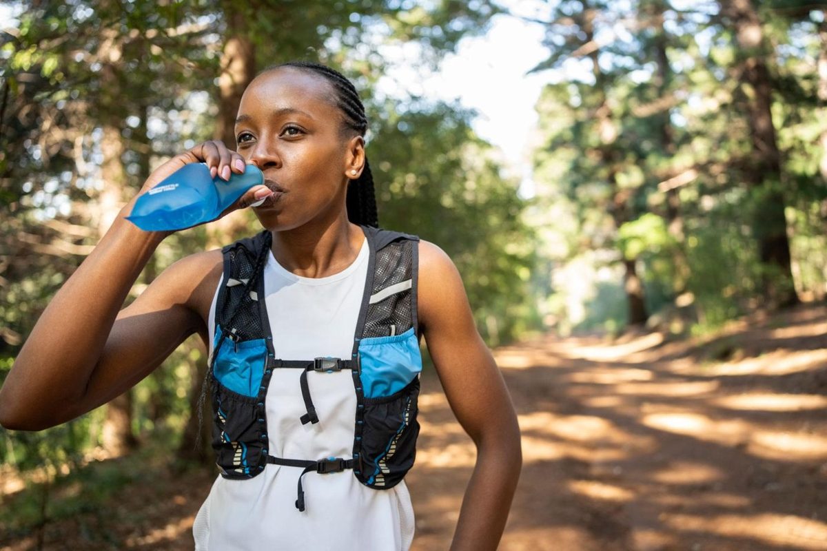 Sportive s'hydratant pendant une course en forêt